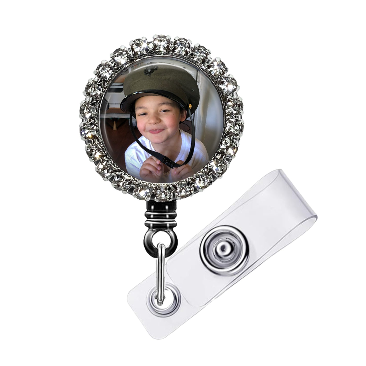 A personalized badge with a photo of a smiling child inside a decorative frame, attached to a clear plastic holder.