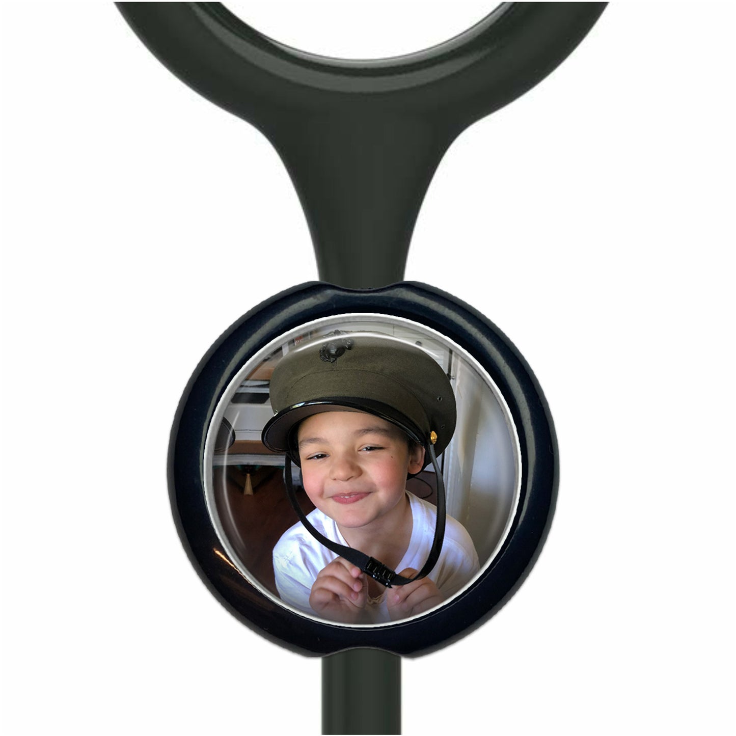 A young boy wearing a helmet is smiling at the camera, with a black stethoscope-like object featuring a circular mirror in the foreground.