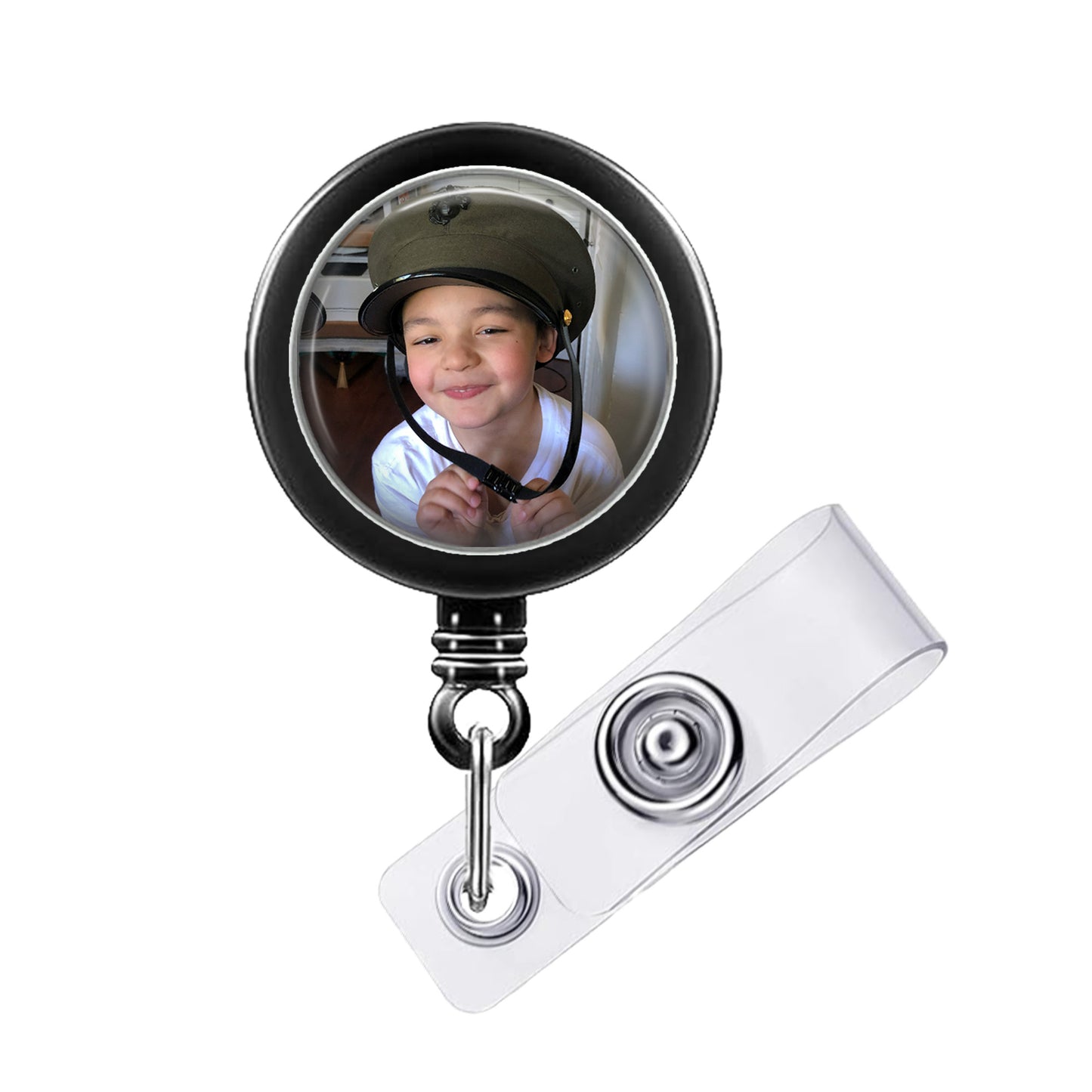 A child wearing a helmet is reflected in a circular badge holder with a clear plastic strap.