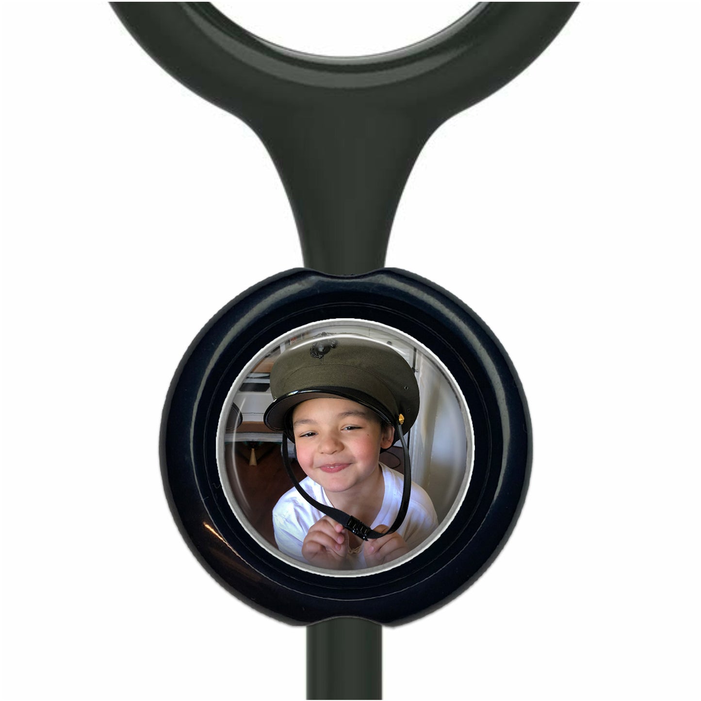 A young boy wearing a hat is smiling at the camera, with a black stethoscope handle visible in the background.