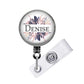 A round badge holder with a floral design and the name "Denise" printed on it.
