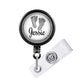 A black and white badge holder with a circular design featuring a pair of baby feet and the name " Jessie" written on it.