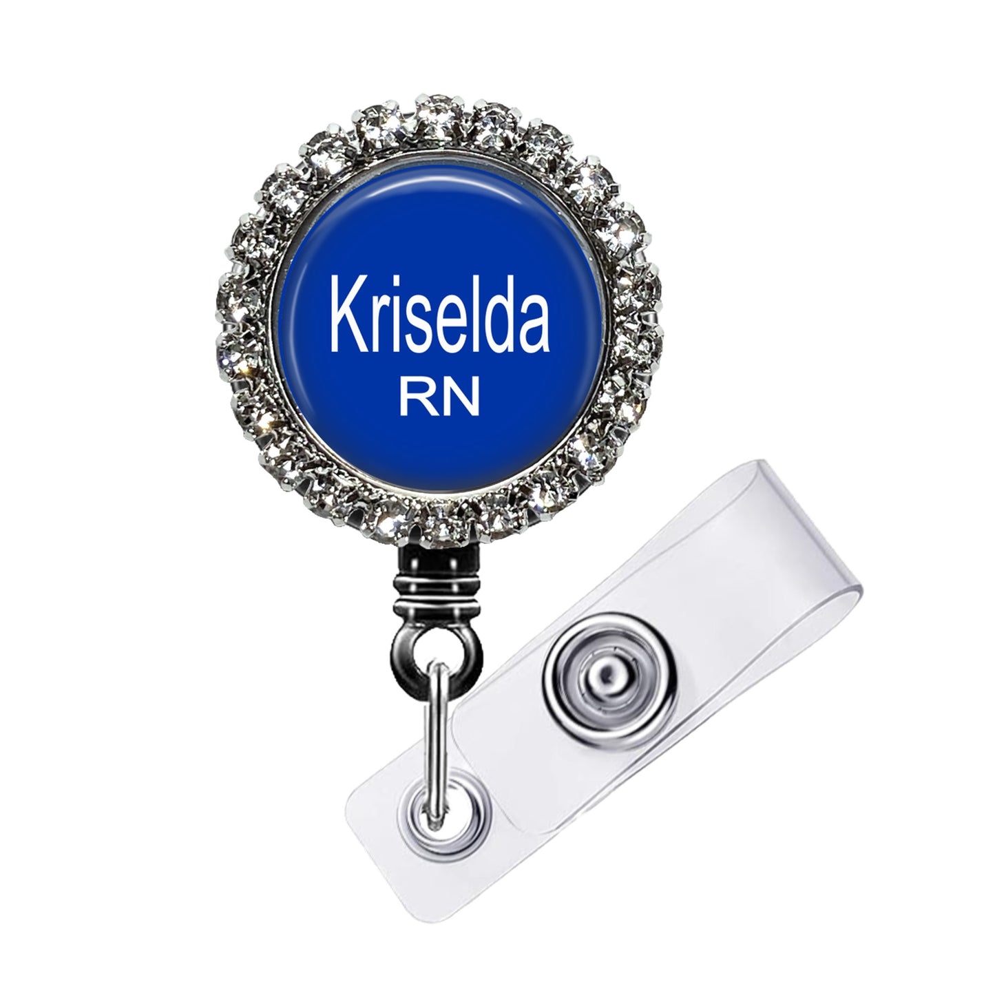 A blue badge with the name "Krisela RN" printed on it, surrounded by a decorative metal frame with rhinestones.