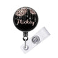 A black and silver badge holder with a personalized name tag attached to it.