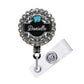A personalized name badge with a black background, silver rhinestones, and a blue hibiscus flower design.