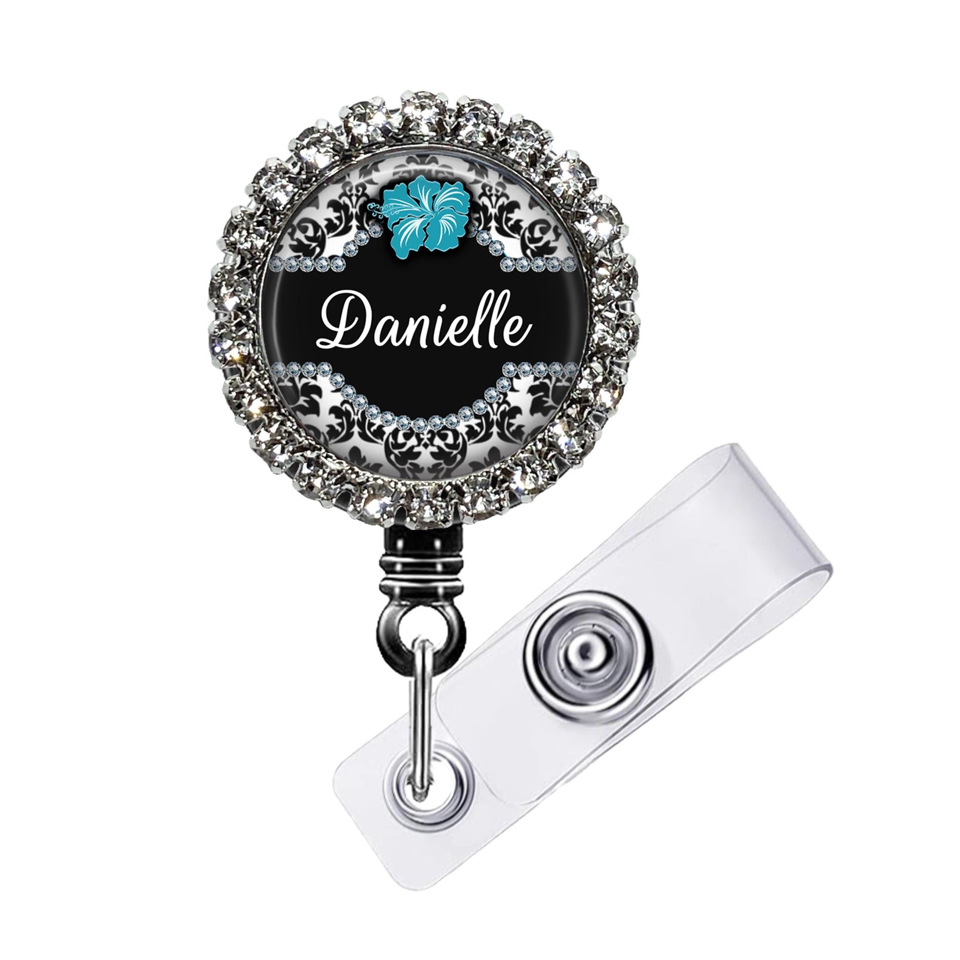 A personalized name badge with a black background, silver rhinestones, and a blue hibiscus flower design.