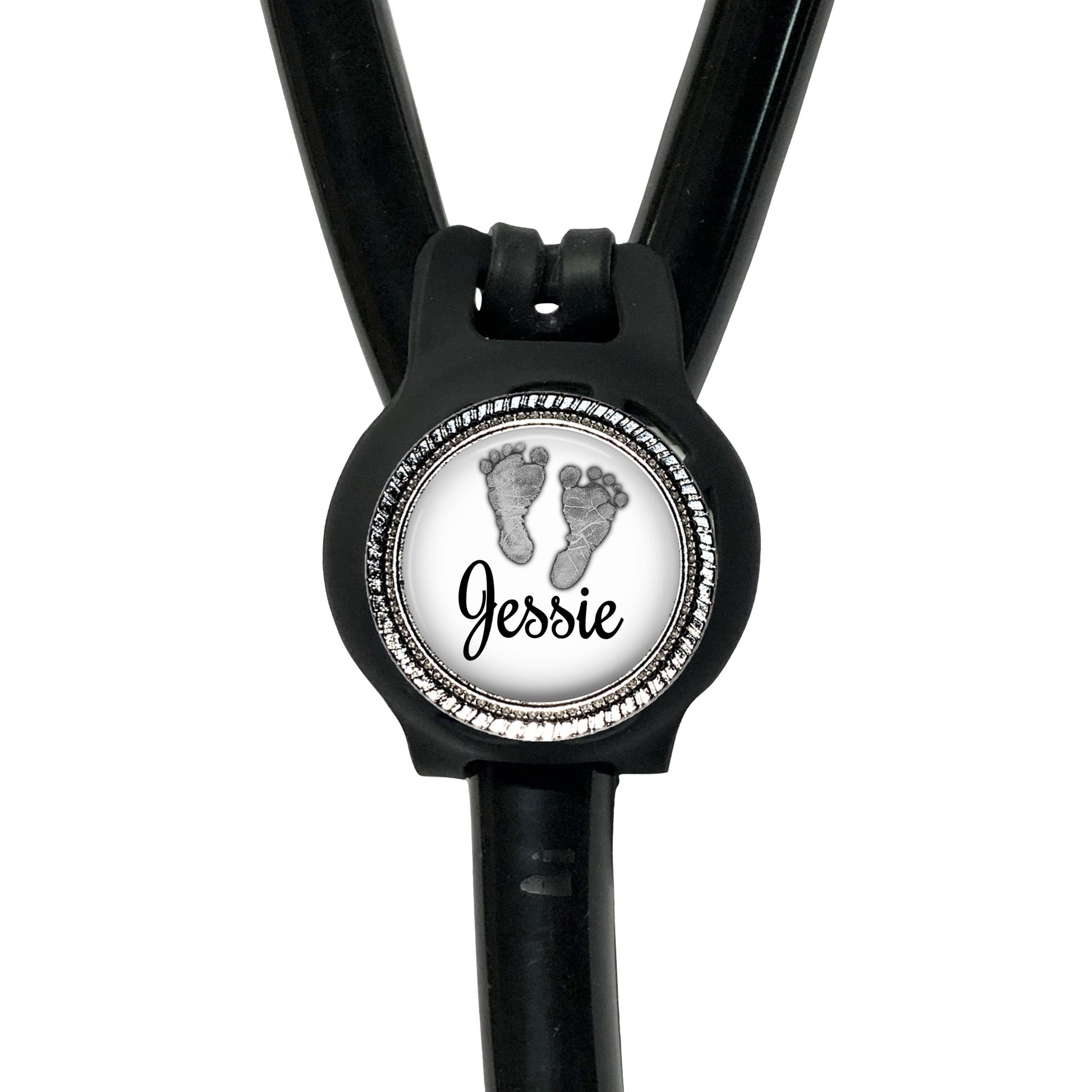 A black stethoscope with a round badge on the front, featuring a pair of footprints and the name " Jessie" written on it.