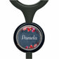 A black stethoscope with a circular badge featuring a floral design and the name "Pamela" written on it.