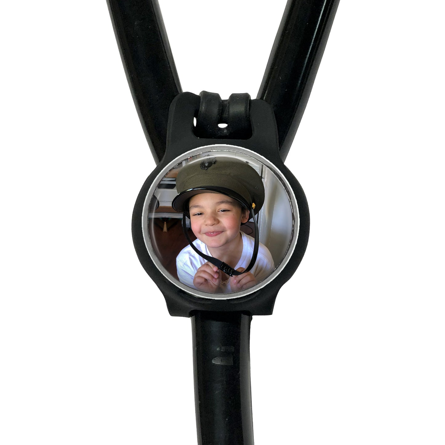 A young boy wearing a helmet is smiling at the camera, with a black stethoscope featuring a circular mirror attached to it.