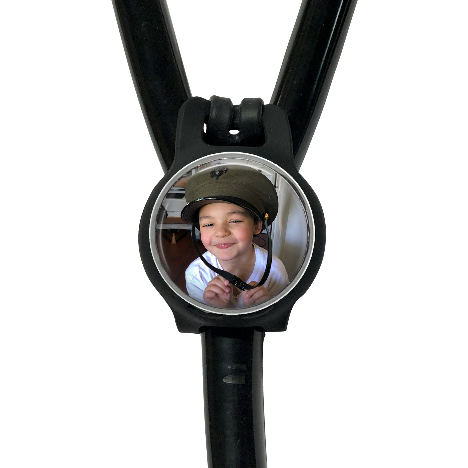 A young boy wearing a helmet is smiling at the camera, with a black stethoscope featuring a circular mirror attached to it.