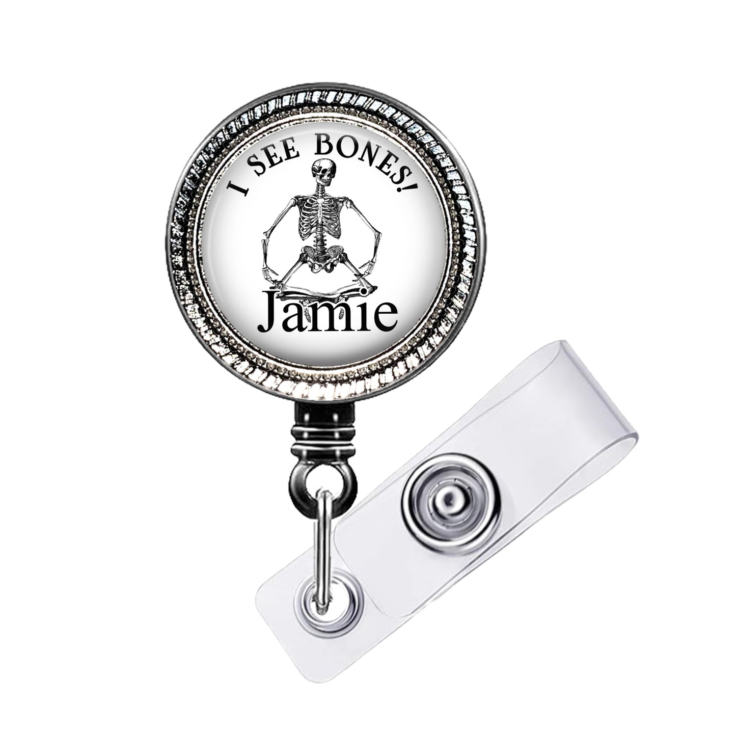 A metal badge with a skeleton image and the text "I SEE BONES! Jamie" printed on it.
