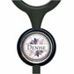 A black stethoscope with a round, decorative charm featuring a floral design and the name "Denise" written on it.